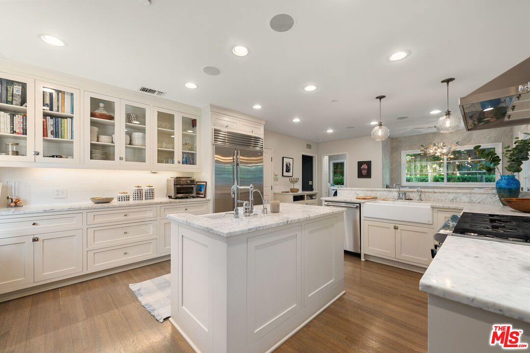 3354 Mandeville Canyon Road Los Angeles, CA 90049 - Photo 28 of 63 a large white kitchen with kitchen island a sink a stove and a chandelier