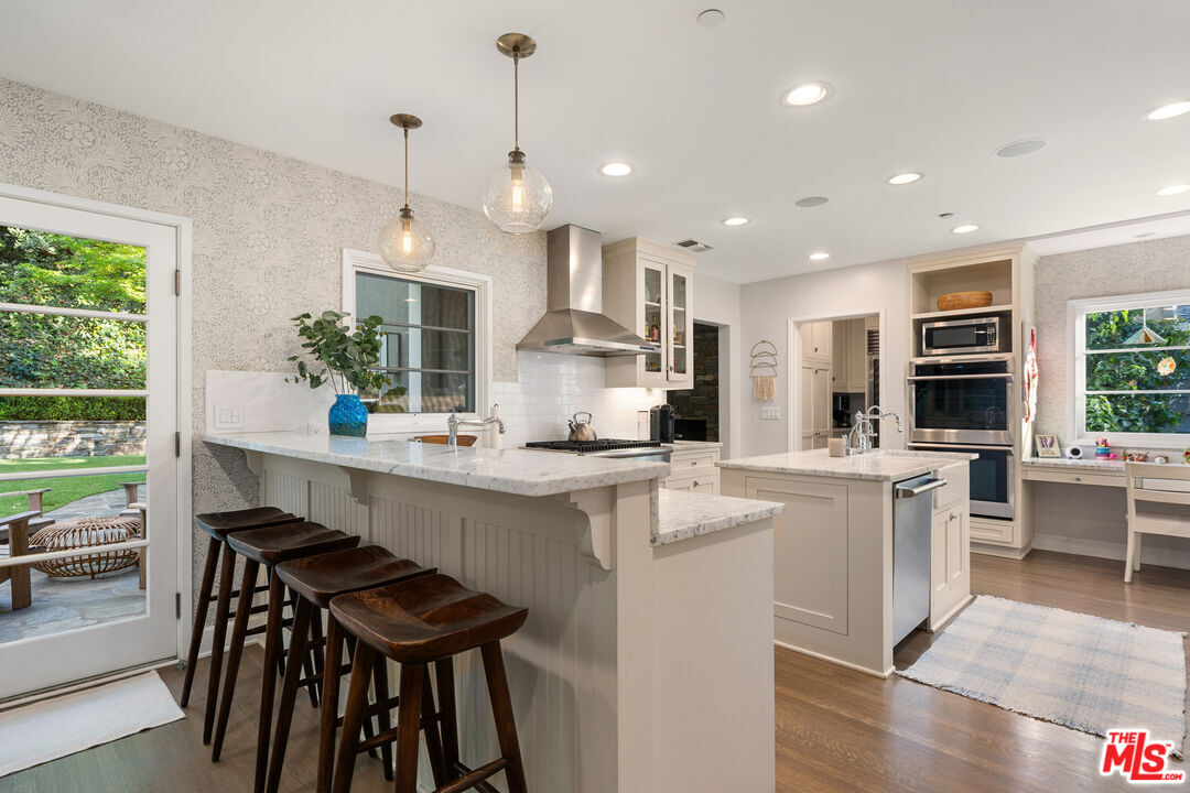 3354 Mandeville Canyon Road Los Angeles, CA 90049 - Photo 30 of 63 a kitchen with stainless steel appliances kitchen island a large island in the center and cabinets