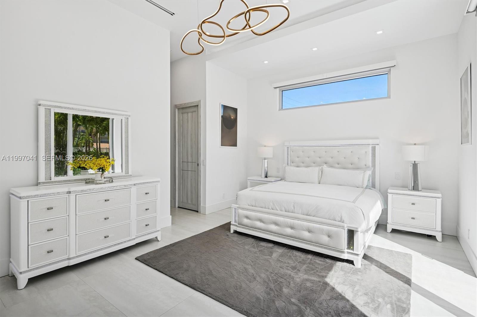 2628 Marcinski Road Jupiter, FL 33477 - Photo 33 of 50 a bedroom with a bed a chandelier and a window