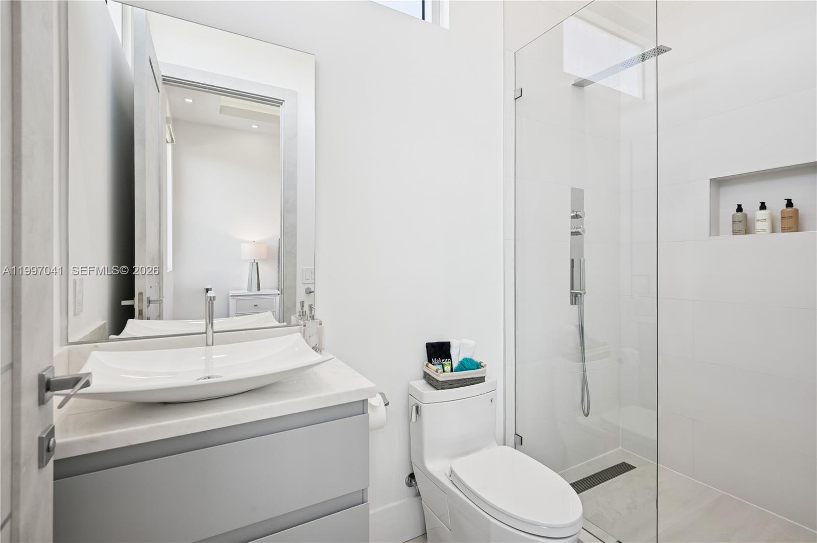 2628 Marcinski Road Jupiter, FL 33477 - Photo 37 of 50 a bathroom with a toilet sink vanity and mirror