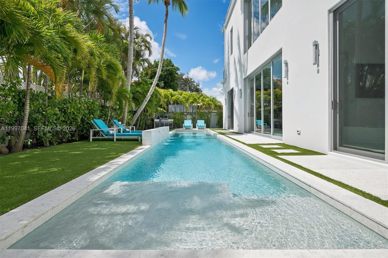 2628 Marcinski Road Jupiter, FL 33477 - Photo 6 of 50 a view of swimming pool with lawn chairs and large trees