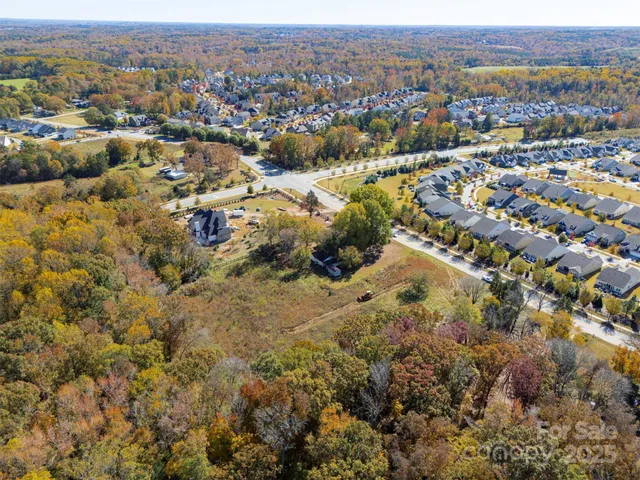 an aerial view of residential house with parking and trees