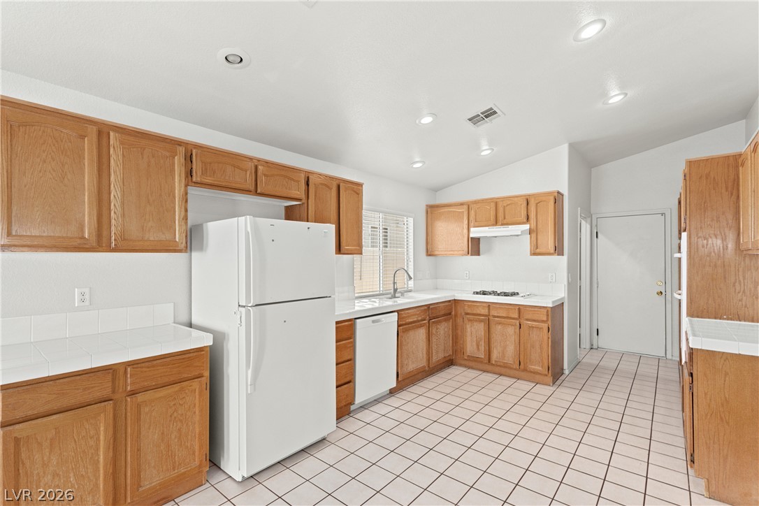 1815 Stablegate Avenue Henderson, NV 89012 - Photo 5 of 28 A well-lit kitchen with natural wood cabinetry and practical appliances provides ample cooking and storage space.