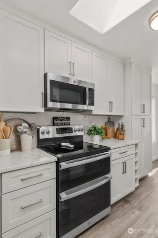 a kitchen with stainless steel appliances granite countertop white cabinets and a stove a oven with white countertops