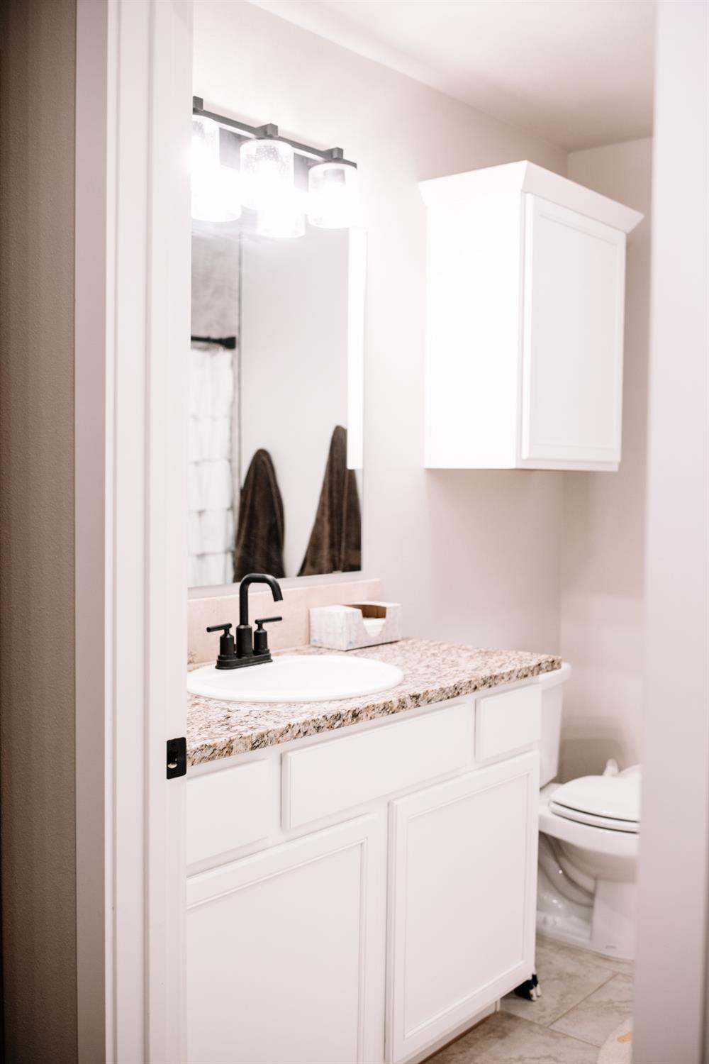 3224 Virginia Avenue Lubbock, TX 79407 - Photo 18 of 39 a bathroom with a granite countertop toilet sink and mirror
