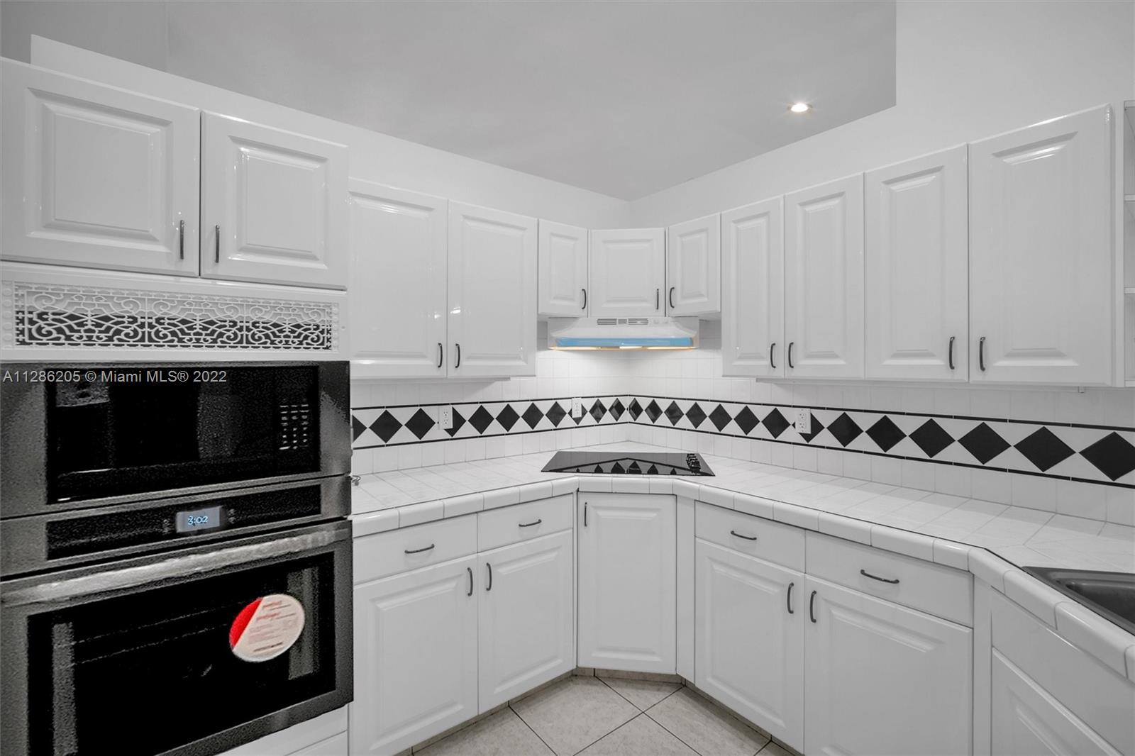 17880 Southwest 66th Street Southwest Ranches, FL 33331 - Photo 14 of 57 a kitchen with white cabinets and black appliances