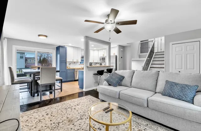 a living room with furniture kitchen view and a wooden floor