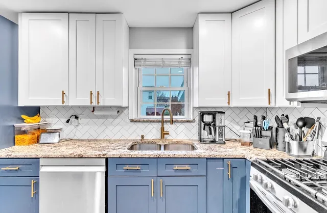 a kitchen with granite countertop a sink a stove and cabinets