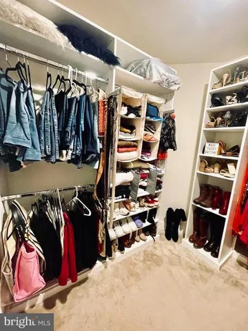 a view of walk in closet with clothes and shoes