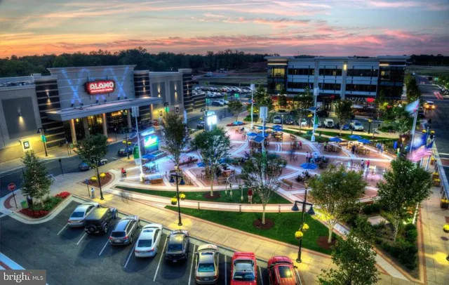 a living room with stainless steel appliances furniture a wooden floor and a window