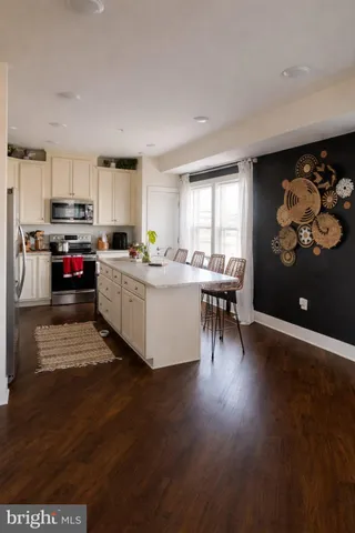 a living room with stainless steel appliances furniture and a wooden floor