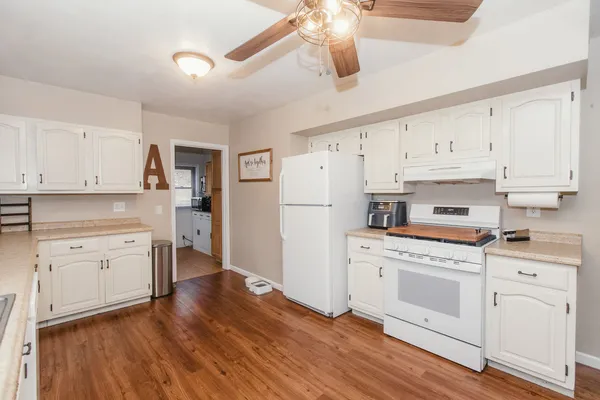 a kitchen with stainless steel appliances granite countertop hardwood floor sink stove dining table and chairs