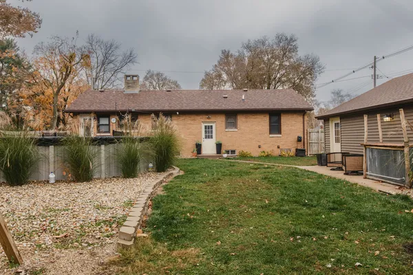 a view of a white house with a small yard and a large tree