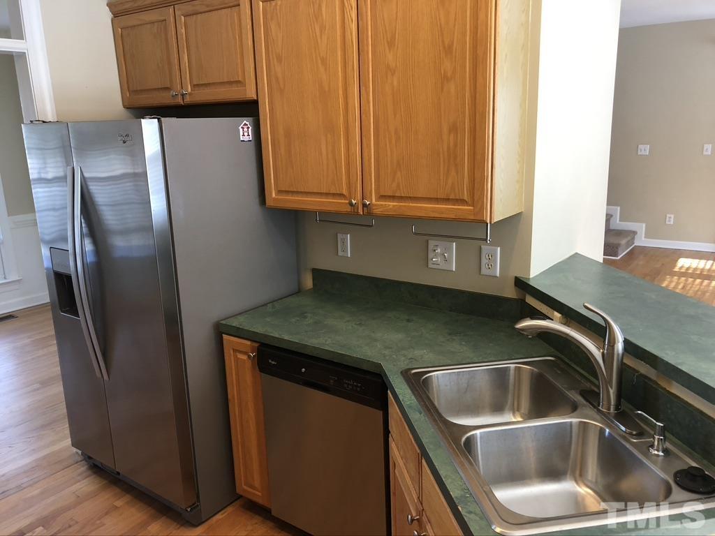 200 Oak Pine Drive Apex, NC 27502 - Photo 11 of 26 a kitchen with stainless steel appliances granite countertop a sink a refrigerator and wooden cabinets