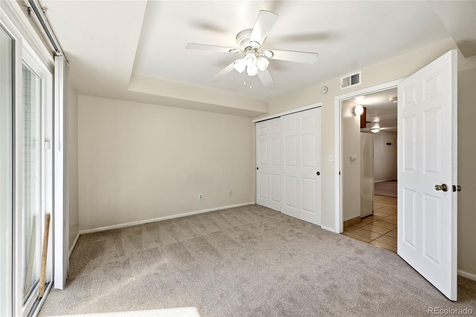 1885 South Quebec Way, Unit A18 Denver, CO 80231 - Photo 14 of 31 an empty room with chandelier fan and windows