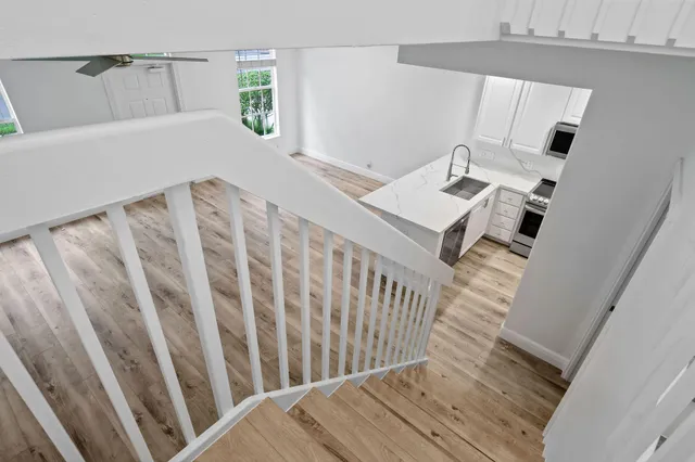an empty room with wooden floor ceiling fan and windows