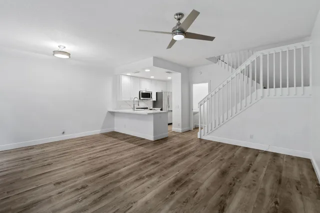 an empty room with wooden floor cabinet and windows