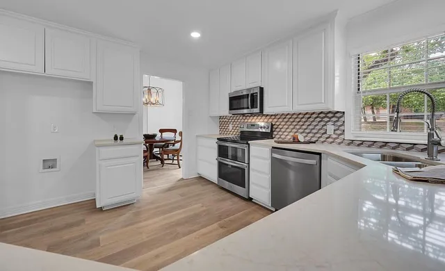 a kitchen with granite countertop a sink cabinets and stainless steel appliances