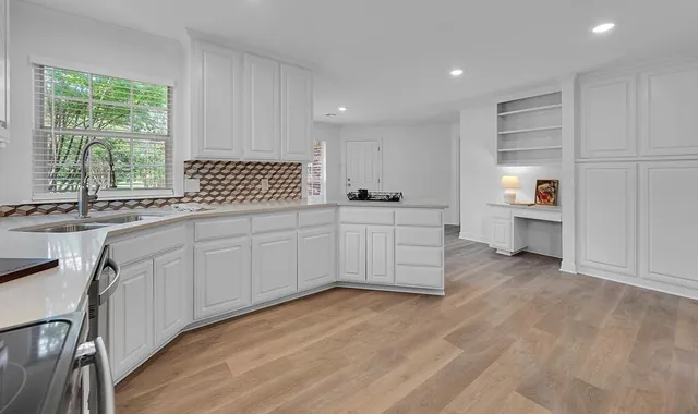 a kitchen with stainless steel appliances a sink dishwasher and white cabinets with wooden floor