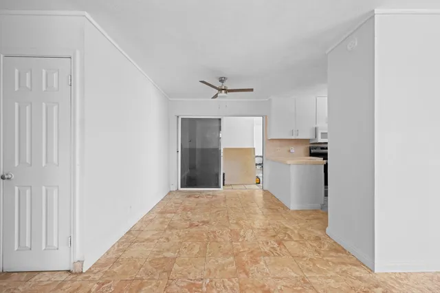 a view of a livingroom with a chandelier fan and kitchen space