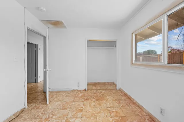 a view of an empty room with window and wooden floor