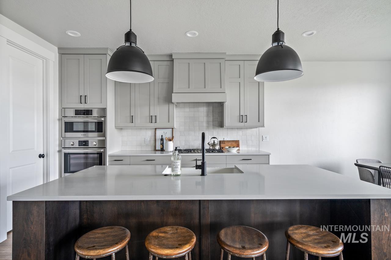 1101 East Crescendo Street Meridian, ID 83642 - Photo 12 of 31 Kitchen with an island with sink, a breakfast bar area, backsplash, double oven, and recessed lighting