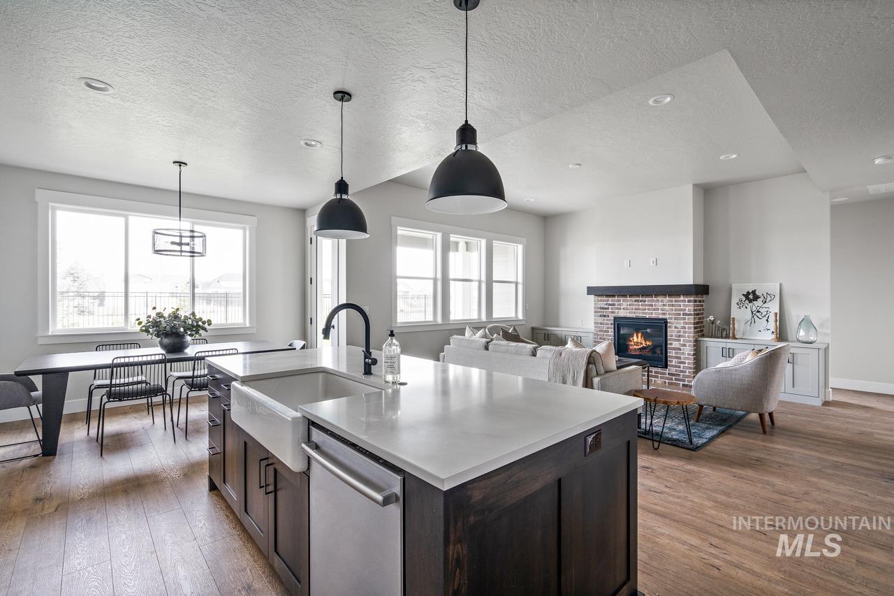 1101 East Crescendo Street Meridian, ID 83642 - Photo 15 of 31 Kitchen with dark brown cabinets, dark wood finished floors, a brick fireplace, dishwasher, and a textured ceiling