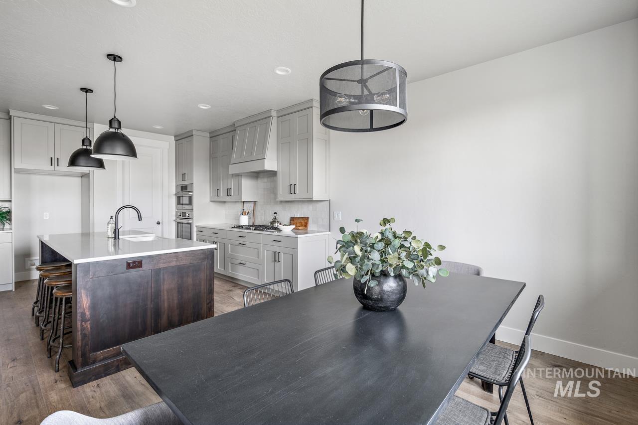 1101 East Crescendo Street Meridian, ID 83642 - Photo 23 of 31 Kitchen featuring a breakfast bar area, a center island with sink, dark wood-type flooring, custom exhaust hood, and pendant lighting
