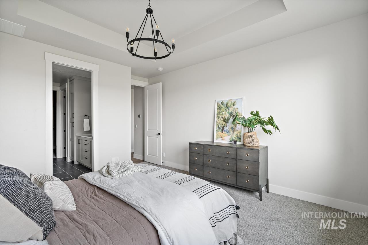 1101 East Crescendo Street Meridian, ID 83642 - Photo 27 of 31 Carpeted bedroom with a tray ceiling, a chandelier, and ensuite bath