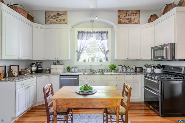 a kitchen with stainless steel appliances a dining table chairs and stove top oven