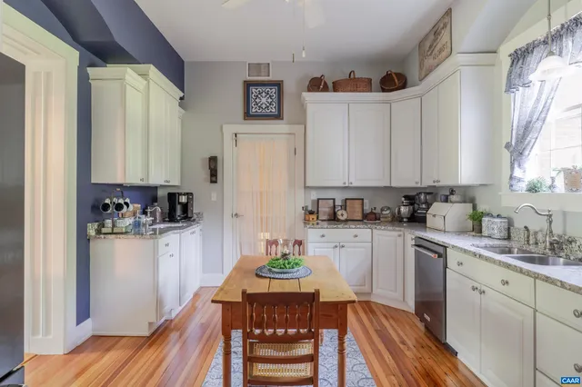 a kitchen with a refrigerator a stove a sink dishwasher and white cabinets with wooden floor