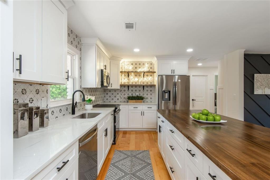 3365 Ardley Road Southwest Atlanta, GA 30311 - Photo 27 of 62 a large kitchen with stainless steel appliances kitchen island granite countertop a lot of counter space and wooden floor