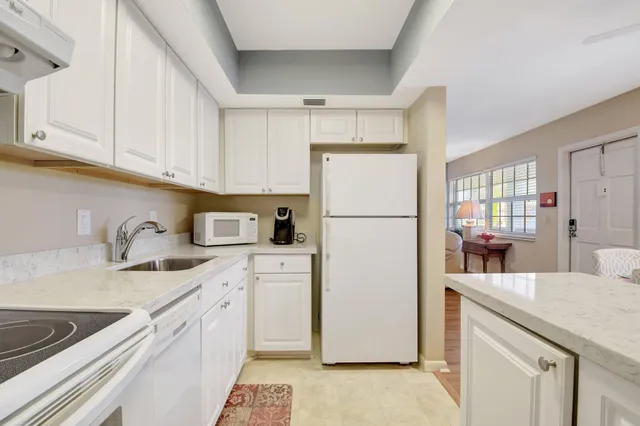 a kitchen with a refrigerator a stove a sink dishwasher and white cabinets with wooden floor