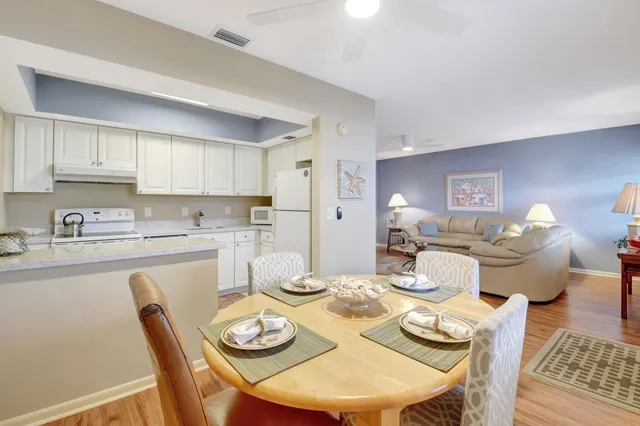 a dining room with wooden floor and kitchen view