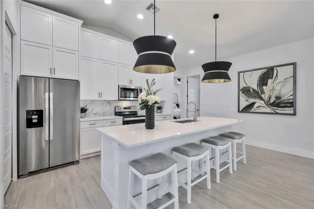 a kitchen with stainless steel appliances granite countertop a sink a refrigerator and a wooden floor