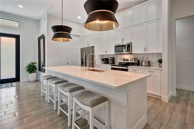 a kitchen with stainless steel appliances kitchen island granite countertop a sink a stove a dining table and chairs