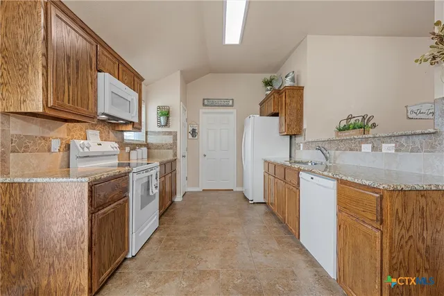 a large kitchen with stainless steel appliances granite countertop a sink and cabinets