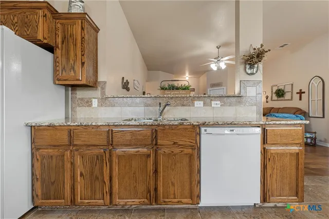 a kitchen with granite countertop a sink cabinets and stainless steel appliances