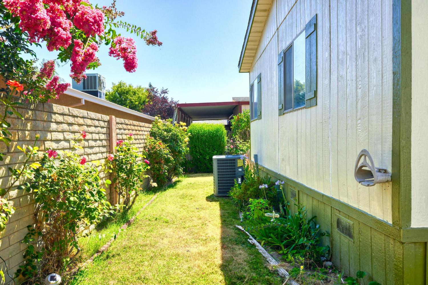 1200 South Carpenter Road, Unit 4 Modesto, CA 95351 - Photo 27 of 31 Back yard featuring a stone block wall, vibrant shrubbery, and a grassy pathway