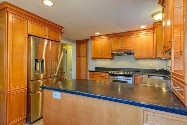 a kitchen with stainless steel appliances granite countertop a refrigerator a stove and a sink with wooden floor