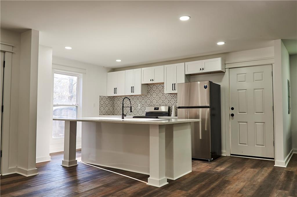 3349 Calhoun Road Northeast Rome, GA 30161 - Photo 9 of 30 a kitchen with stainless steel appliances granite countertop a refrigerator a sink a stove and white cabinets with wooden floor