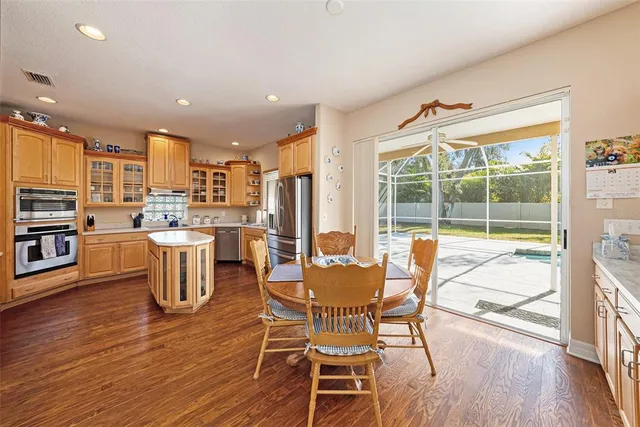 a dining room with stainless steel appliances a dining table chairs and view of living room