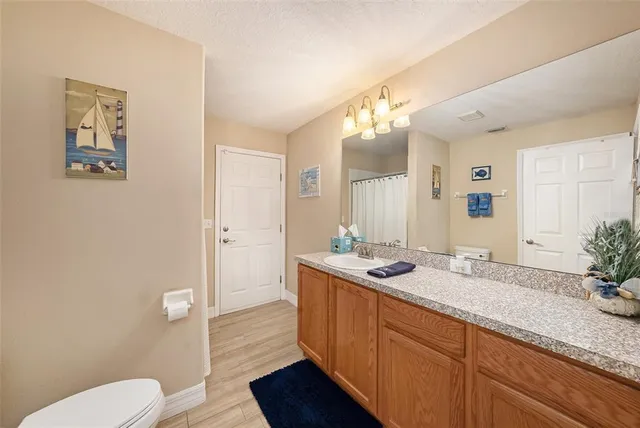 a spacious bathroom with a granite countertop sink a toilet and a mirror
