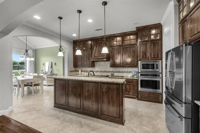 a kitchen with kitchen island granite countertop a stove refrigerator and dining table
