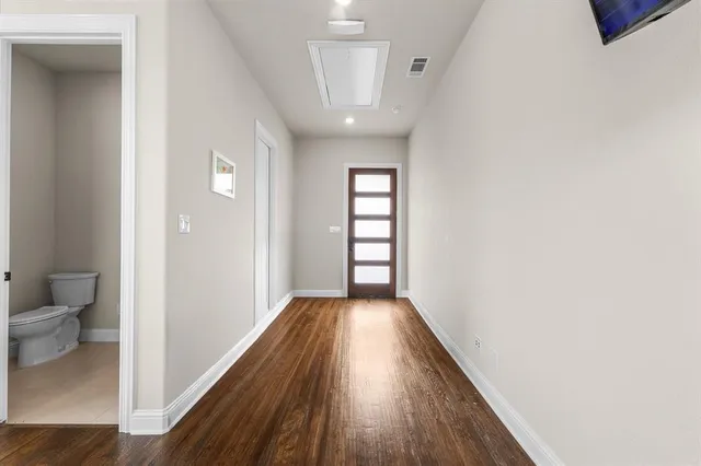 a view of a hallway with wooden floor and a bathroom