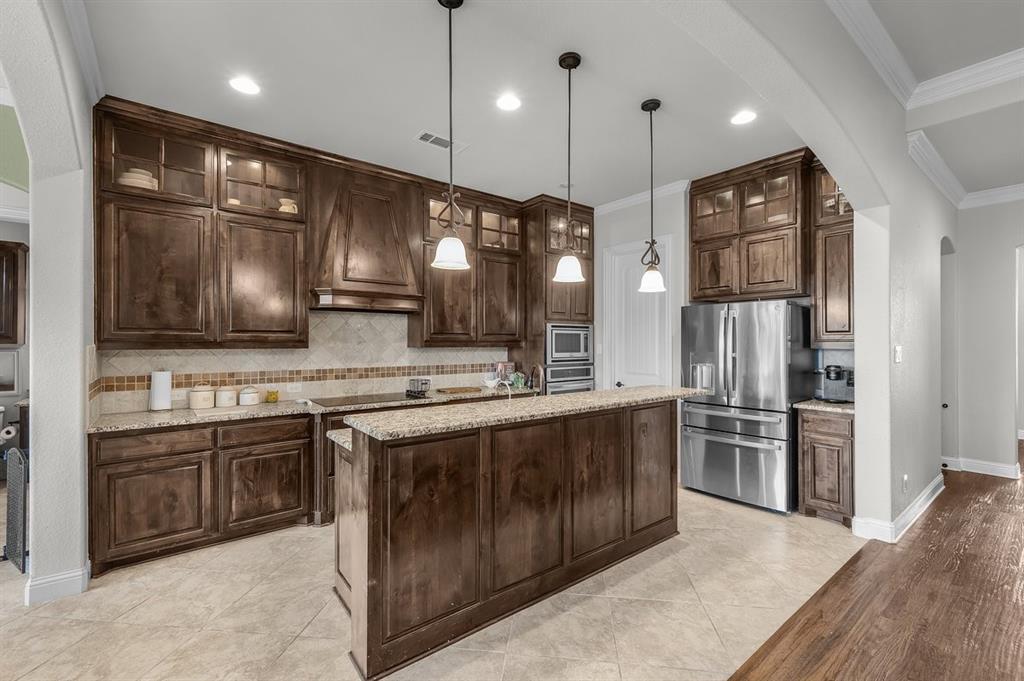 228 Parc Oaks Drive Aledo, TX 76008 - Photo 6 of 40 a large kitchen with stainless steel appliances kitchen island granite countertop a stove a sink dishwasher a refrigerator and wooden cabinets with wooden floor