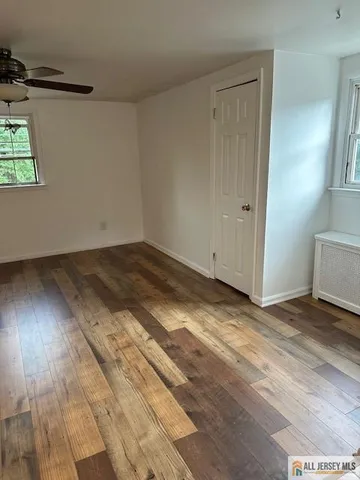an empty room with wooden floor cabinet and windows