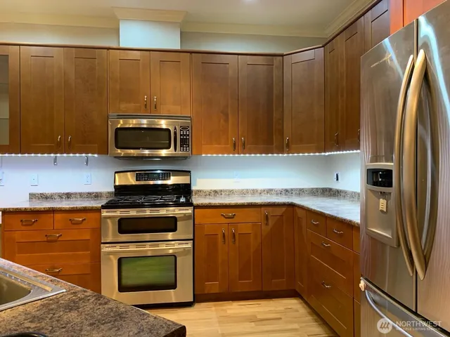 a kitchen with stainless steel appliances wooden cabinets and a stove top oven