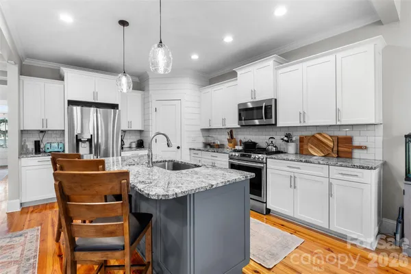 a kitchen with granite countertop a stove a sink a oven a dining table and chairs