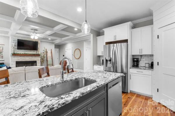 a view of a dining room and livingroom furniture wooden floor a rug a flat screen tv a rug a painting and a chandelier